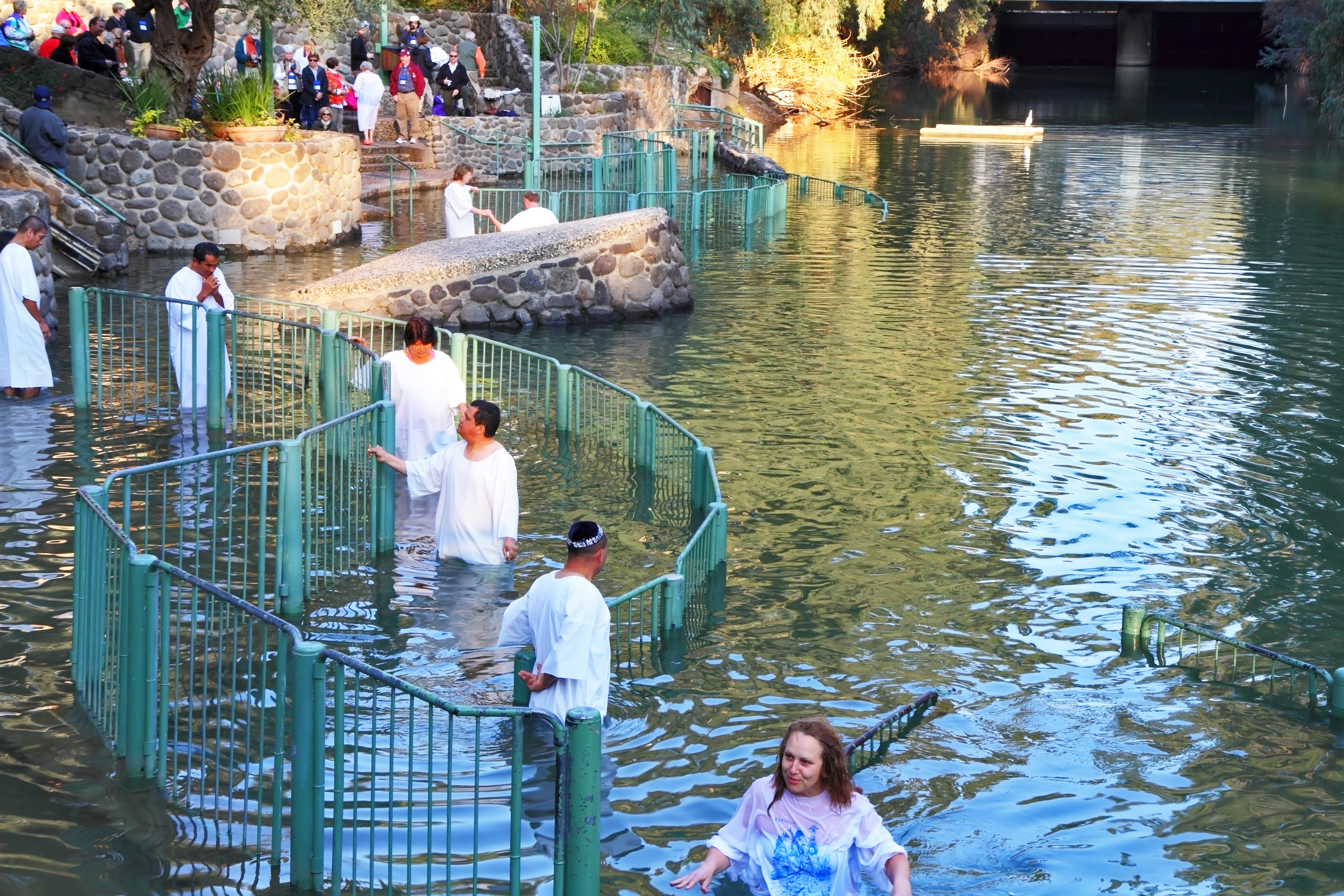 Yardenit, Israel - January 21: Christian pilgrims ritual baptism in the waters of the Jordan River. Pilgrims enter the water, dressed in special white christening shirt